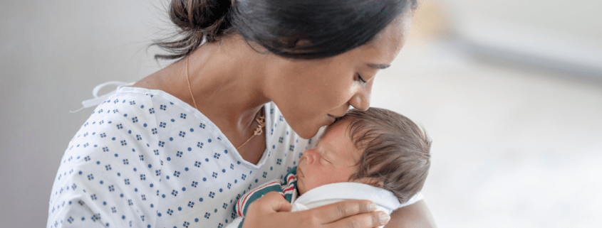 A mother kisses her newborn with moderate head molding.