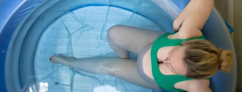 A birthing person sits in a birth pool.