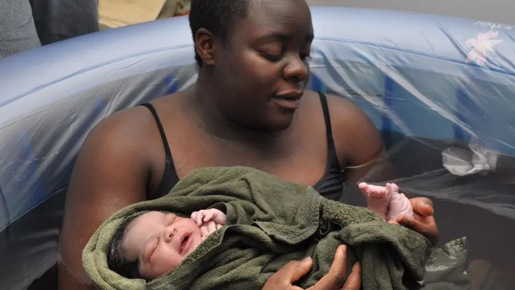 A birthing person holds their baby in a birth pool after their waterbirth.