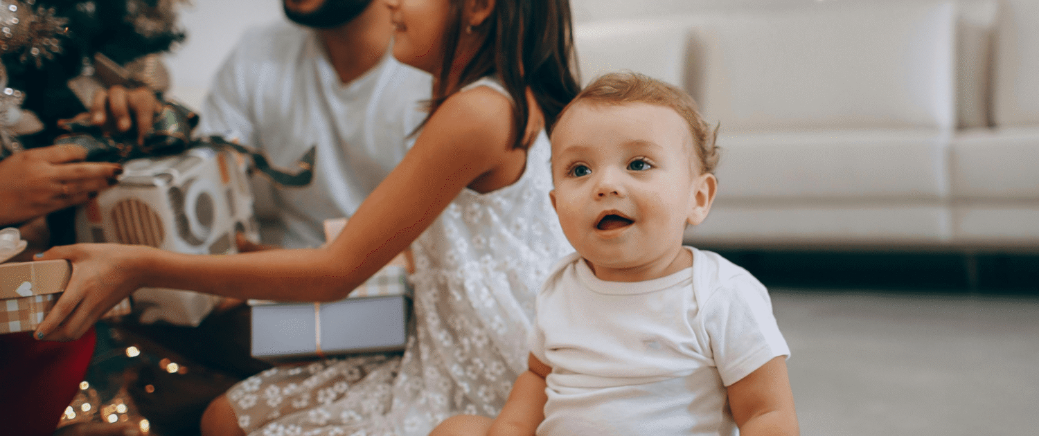 A new baby in Baltimore Maryland smiles as their family opens gifts of experiences from a gift guide.