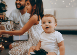 A new baby in Baltimore Maryland smiles as their family opens gifts of experiences from a gift guide.