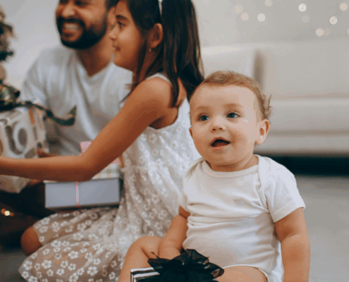 A new baby in Baltimore Maryland smiles as their family opens gifts of experiences from a gift guide.