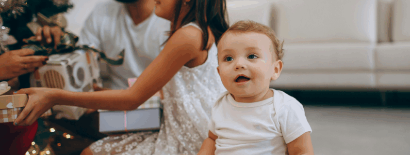 A new baby in Baltimore Maryland smiles as their family opens gifts of experiences from a gift guide.